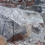 drilling and pouring of rock breaking chemical on massive boulders on a mine