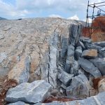 drilling and pouring of rock breaking chemical on massive out crop of rock on a mine